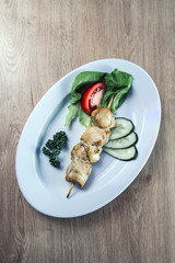 barbecue on wooden skewers with slices of lemon and fresh vegetables