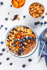 chocolate oatmeal porridge with blueberry, nuts, banana, dried apricot for healthy breakfast. Top view