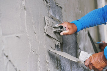 hand of worker plastering cement on wall