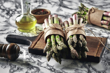 An edible, raw stems of asparagus on a marble background.