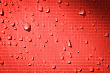Large drops of water on a red textile with a waterproof effect. Water-repellent impregnation....