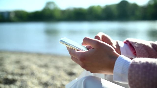 Young woman with smartphone writing text message