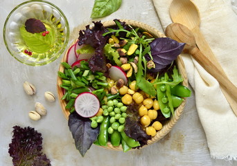Healthy vegetarian bowl salad with chickpeas, green peas, radish and pistachios,  view from above