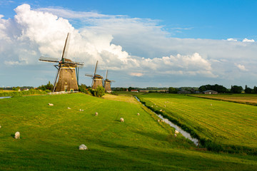 old wind mill landscape with blue sky clouds and lambs