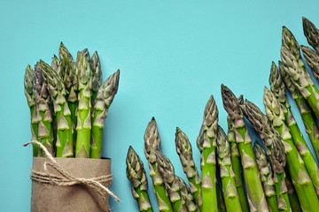 An edible, raw stems of asparagus on blue background.