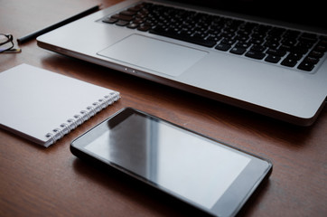 Laptop, smartphone, notebook and pen on desk side view. The concept of technology, communication, work, education