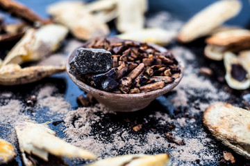 Popular Indian and Asian mukhwas or mouth freshener i.e. Aam Ki Ghuthli Ka Mukhwas consisting of ghee and hard-boiled mango seeds in a bowl on a wooden surface.Along with some raw dried mango seeds.