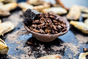 Popular Indian and Asian mukhwas or mouth freshener i.e. Aam Ki Ghuthli Ka Mukhwas consisting of ghee and hard-boiled mango seeds in a bowl on a wooden surface.Along with some raw dried mango seeds.