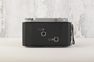 Old medium format rangefinder film camera on white cement background.