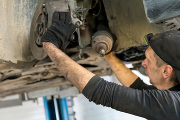 Work in the service station, suspension repair, CV joint removal - obrazy, fototapety, plakaty