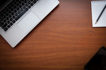 Wood office desk table with laptop, glasses, notebook, pen, smartphone. Top view, copy space