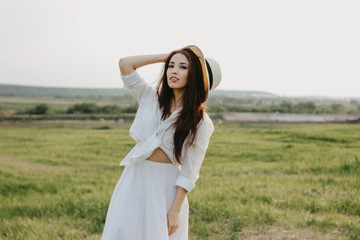 Portrait of charming carefree long hair asian girl in white clothes and straw hat enjoys life in...