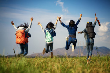A group of women jump together in the grass field.Beautiful group of girls traveling together on...