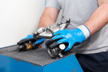 Automotive worker holding new part of car engine