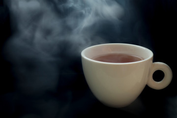 Cup of hot coffee drink with smoke on a black background