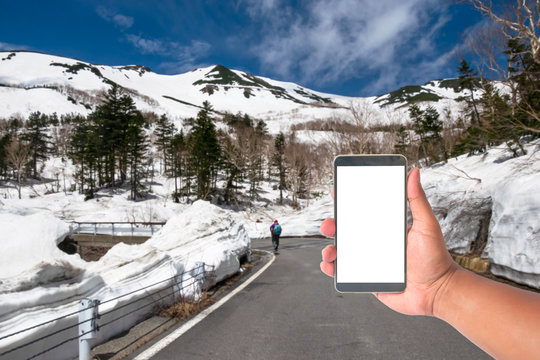 Hand Hold Mobile Phone With A Road Of Snow Wall Japan Alps Mountain, Japan.