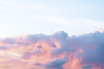 A dramatic cloud of blue, orange and pink on the blue sky in the form of a cat.
