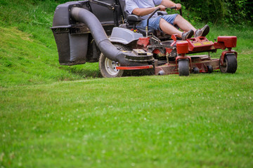 Gardener mowing the lawn cutting grass with gardening tools