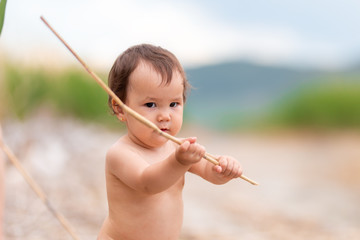 small girl without clothes on beach at sea play with sticks