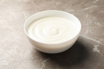 Bowl of sour cream yogurt on grey background