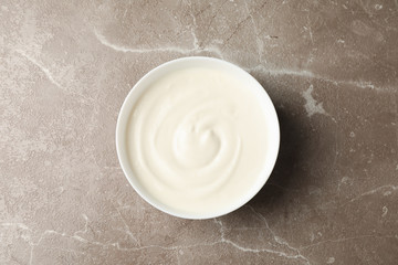 Bowl of sour cream yogurt on grey background