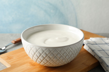 Obraz na płótnie Canvas Composition with yogurt in bowl on grey table against blue background