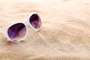 Modern sunglasses on the beach sand