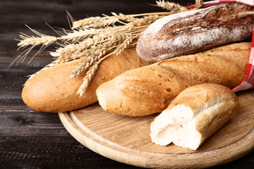 Fresh baguettes with wheat ears on brown wooden table