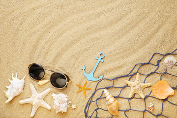 Seashells with fishing net and sunglasses on beach sand