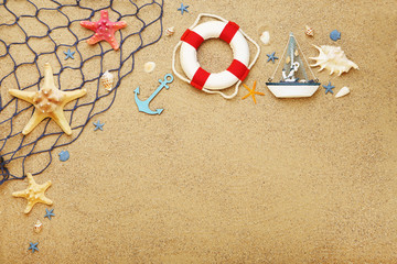 Fototapeta na wymiar Seashells with fishing net and lifebuoy on beach sand