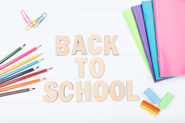 Text Back To School with stationery on white wooden table
