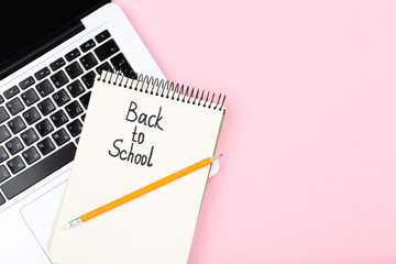Text Back To School with laptop and pencil on pink background