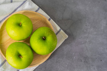 Fresh green apples in dish wooden, with Hand towel on Cement surface, kitchen in home.