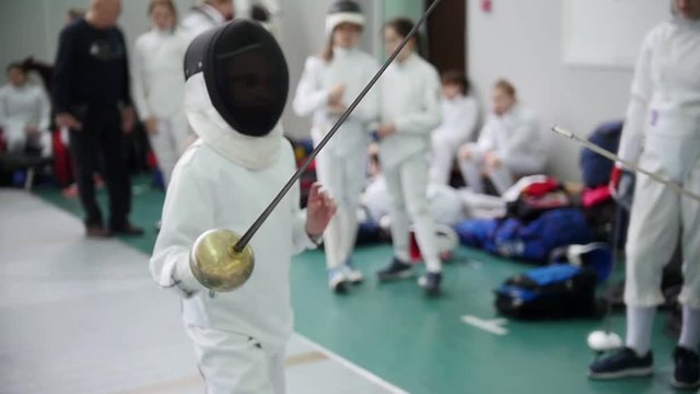 Teen girl strikes the enemy with her sword at the fencing bout