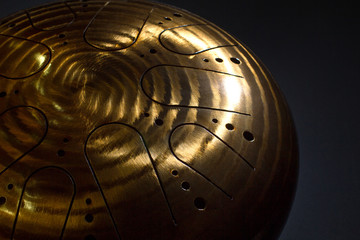 Golden hang drum on a black background, near view, closeup