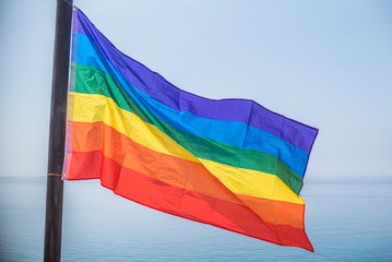 Pride flag with lgbti colors waving in the air in front of the sea