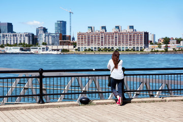 Fototapeta na wymiar Young redhead female watching the scenery of Montreal city and the Saint Lawrence river on a sunny summer day in Quebec, Canada.