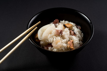 Dish of rice with seafood on black