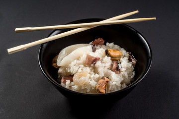 Dish of rice with seafood on black