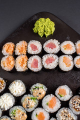 Japanese sushi rolls set served on black plate on dark background