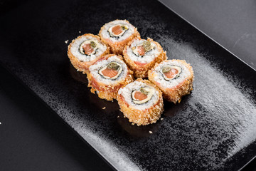 Sushi rolls on black plate with chopsticks