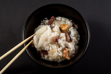 Dish of rice with seafood on black