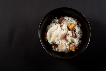 Dish of rice with seafood on black
