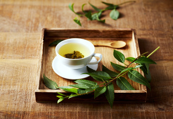 A cup of green tea on wooden tray  with green leaves. Healthy lifestyle. Copy space