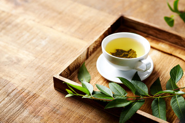 A cup of green tea on wooden tray  with green leaves. Healthy lifestyle. Copy space