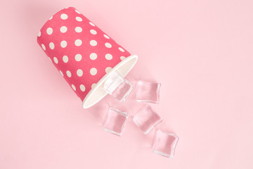 High angle view of disposable cup with ice cubes abstract isolated on pastel rose.