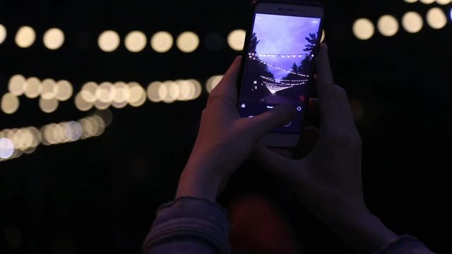 girl shoots on a smartphone night lights gerland Christmas and new year background HD video Slow motion