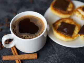 A Cup of fragrant espresso coffee and cheesecakes with chocolate and cinnamon