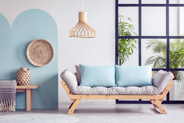 Urban jungle in bright white and blue living room interior with scandinavian futon sofa