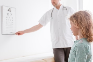 Fototapeta premium Ophthalmologist shows a small boy an eye test chart